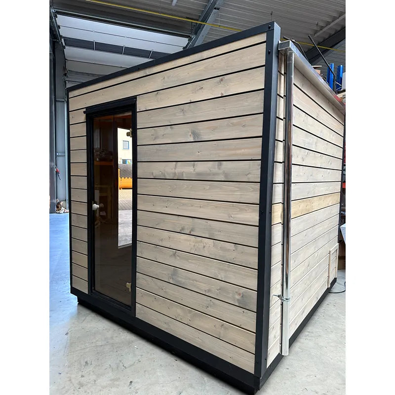 KOBA Cube Gartensauna moderne quadratische Form mit Holzverkleidung und schwarzem Rahmen in Werkstatt