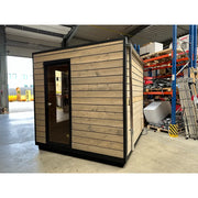 KOBA Cube Gartensauna - Moderne quadratische Form mit Holzverkleidung und schwarzer Tür in Lagerhalle