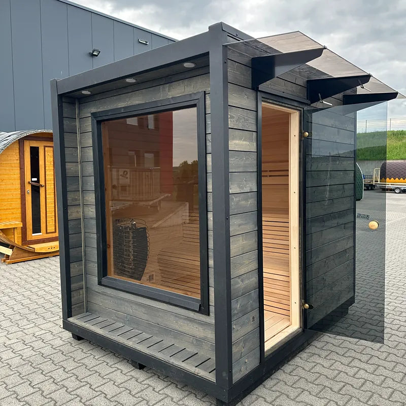 KOBA Cube Gartensauna - Moderne quadratische Form mit schwarzem Rahmen, Glastür und Holzinnenraum auf Ausstellungsgelände