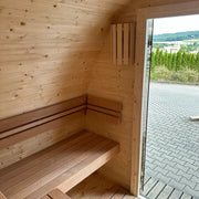 KOBA Iglu Gartensauna Innenraum mit Holzbänken, gewölbtem Holzdach und offener Glastür zum Garten