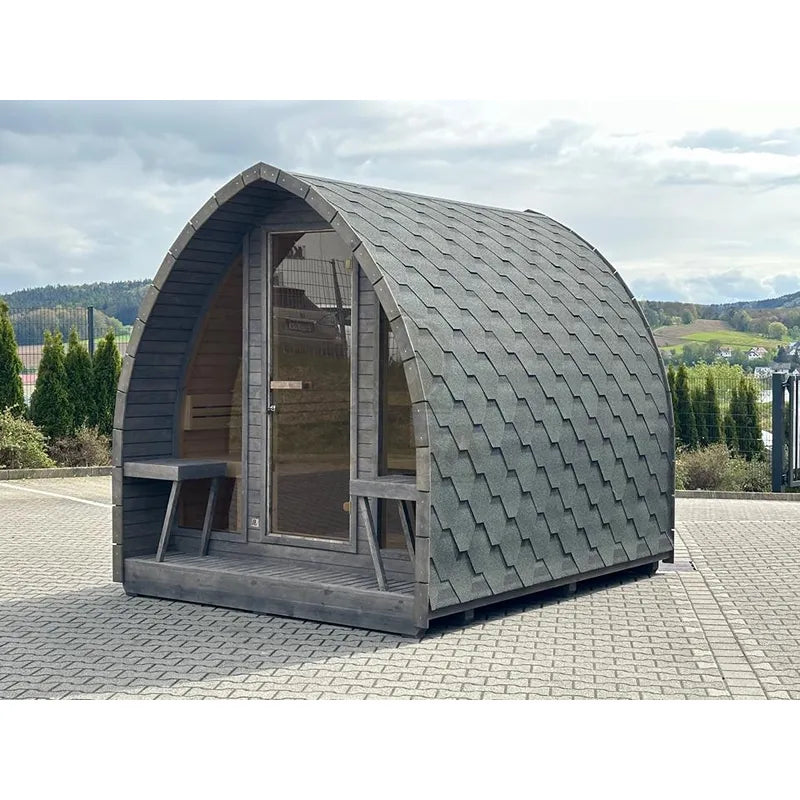 KOBA Iglu Gartensauna mit charakteristischer Iglu-Form in Grau, aufgestellt auf Pflastersteinen im Garten mit Landschaftsblick