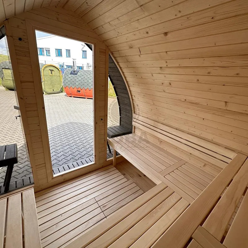 KOBA Iglu Gartensauna Innenraum mit Holzbänken, offene Tür zeigt Garten