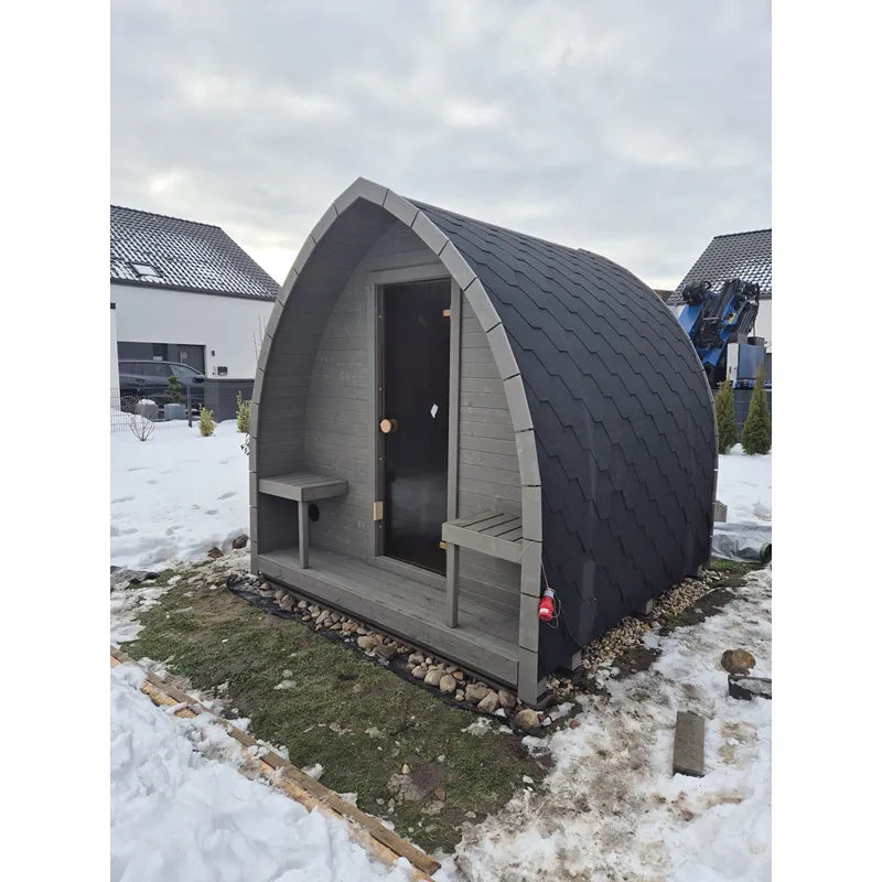 KOBA Iglu Gartensauna - Besondere Iglu-Form mit charakteristischer Iglu-Kuppel, grauer Holzverkleidung und dunklem Schieferdach im Garten