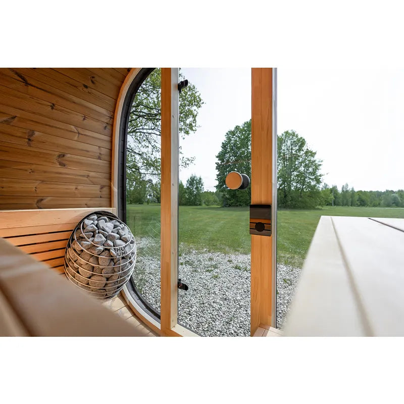 Leil Black Cube Classic Gartensauna mit Holzbänken, großen Panoramafenstern und Saunaofen im grünen Gartenumfeld