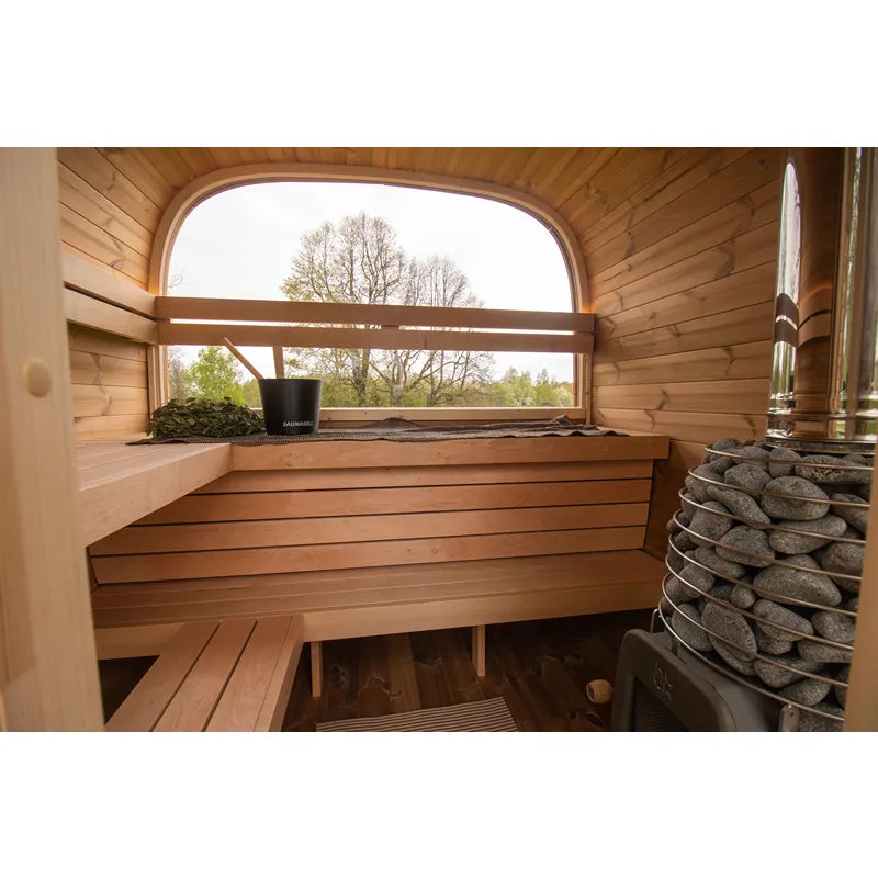 Leil Dice Comfy Gartensauna 4 Personen 2 Räume von Leil Saunas – Innenansicht mit Holzbänken, Saunaofen und großem Fenster