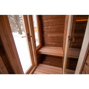 Leil Dice Dual Gartensauna von Leil Saunas – Innenraum mit Holzbänken und geöffneter Eingangstür zum verschneiten Garten