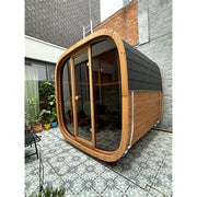 Leil® Dice Solo Gartensauna 5 Personen 4,5 m² mit Holzrahmen und großen Glastüren im modernen Innenhof