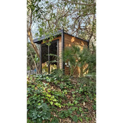 Leil Patio S Gartensauna 4 Personen mit Holzfassade und großem Fenster, umgeben von Garten und Bäumen