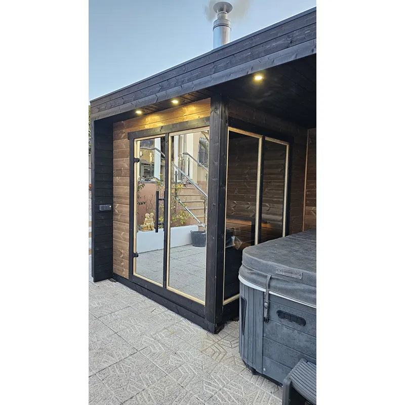 Leil Patio S Plus Gartensauna mit Überdachung im Garten mit beleuchteter Terrasse und Glastüren