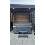Leil Patio S Plus Gartensauna mit Überdachung, dunkelgraues Holzmodell mit integriertem Whirlpool und Treppeneinstieg unter moderner Terrassenüberdachung