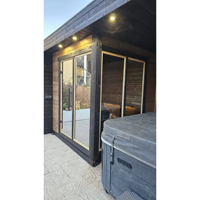 Leil Patio S Plus Gartensauna mit Überdachung, moderne schwarze Saunahütte mit Glastüren und LED-Beleuchtung im Garten