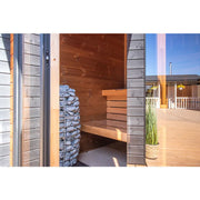 Leil® Patio XS Gartensauna 4 Personen von Leil® Saunas mit offener Tür, Holzinnenraum und Steinofen auf sonniger Terrasse
