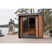 Leil® Patio XXS Gartensauna 3 Personen von Leil® Saunas mit Holzverkleidung am See, Paar in Bademäntel davor