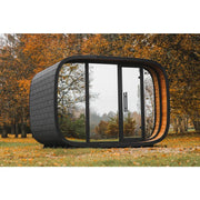 Leil® Round Cube Double Premium Gartensauna 2 Räume mit rundem Design, schwarzer Außenfassade und großen Glasfenstern im Herbstgarten