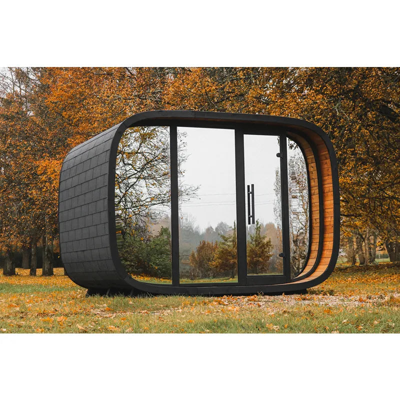 Leil® Round Cube Double Premium Gartensauna 2 Räume mit rundem Design, schwarzer Außenfassade und großen Glasfenstern im Herbstgarten
