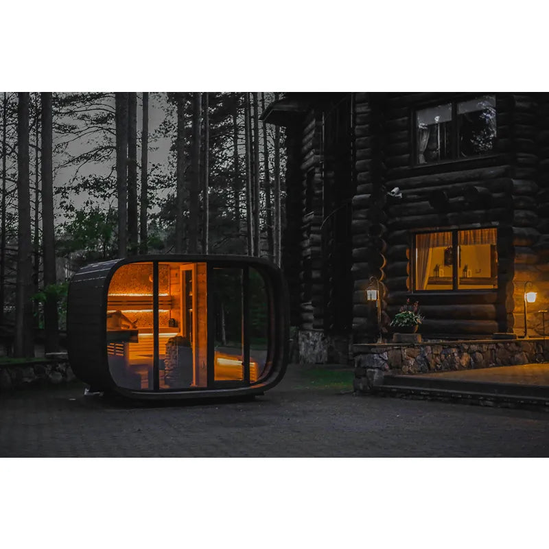 Leil® Round Cube Double Premium Gartensauna 2 Räume von Leil® Saunas im Wald bei Nacht mit warmem Licht