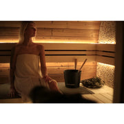 Frau in Handtuch sitzt in Leil® Round Cube Double Gartensauna mit Holzbänken und Saunazubehör