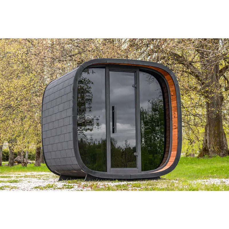 Leil Round Cube Mini – Gartensauna 4 Personen von Leil Saunas mit schwarzem Holzschindel-Design und großem Glasfenster im Garten