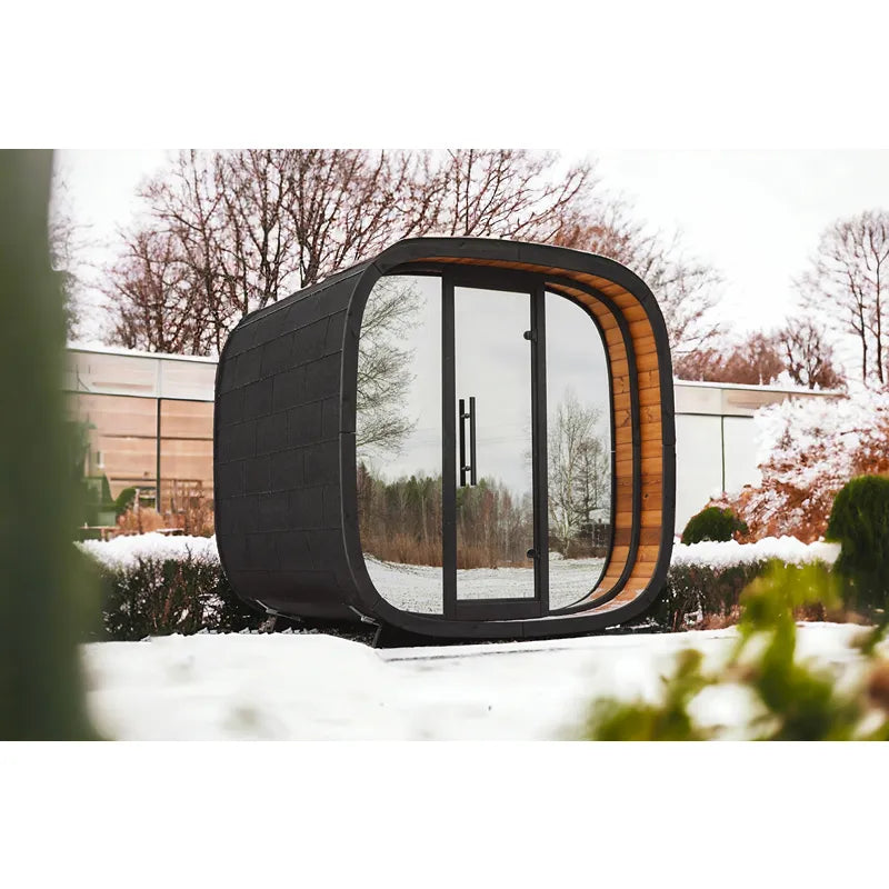 Leil Round Cube Mini Gartensauna 4 Personen von Leil Saunas mit schwarzer Außenseite und Holzinnenraum im winterlichen Garten