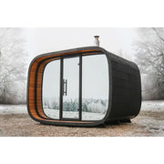 Leil Round Cube Single Premium Gartensauna 1 Raum mit schwarzer Außenseite, großen Panoramafenstern und orangefarbenem Holzinnenraum im winterlichen Garten