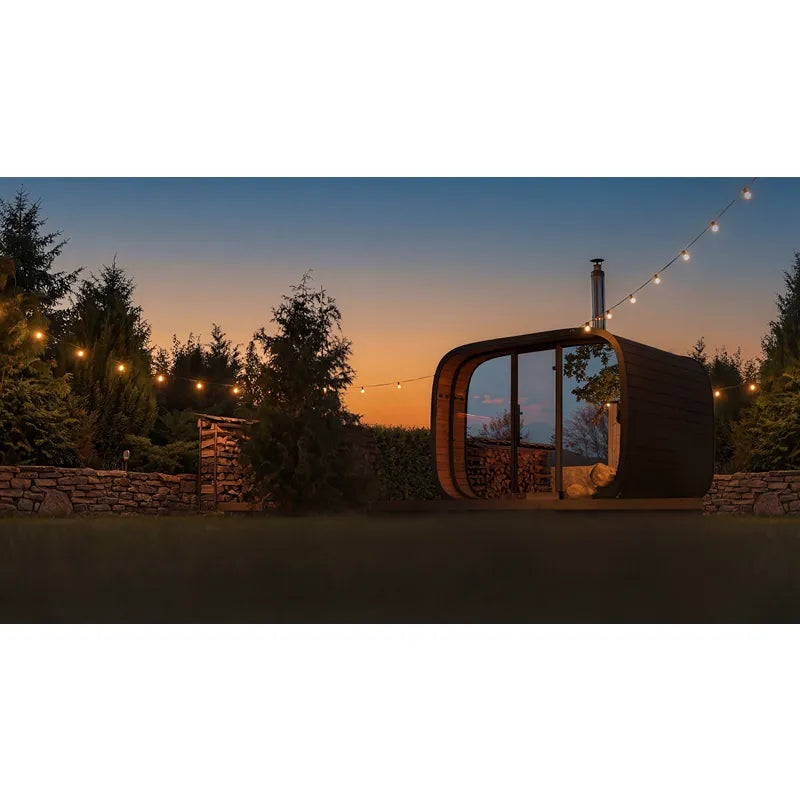 Leil Round Cube Single Premium Gartensauna 1 Raum in modernem Garten bei Sonnenuntergang mit Holzlagerung