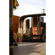 Leil Round Cube Single – Premium Gartensauna 1 Raum von Leil Saunas im Garten mit rundem Design, Holzverkleidung und großen Glastüren