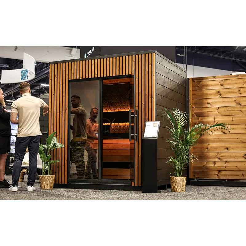 Leil® Viva 210 Gartensauna 4 Personen mit Liege von Leil® Saunas auf Messe, Holzverkleidung mit Glastür, Personen im Innenraum