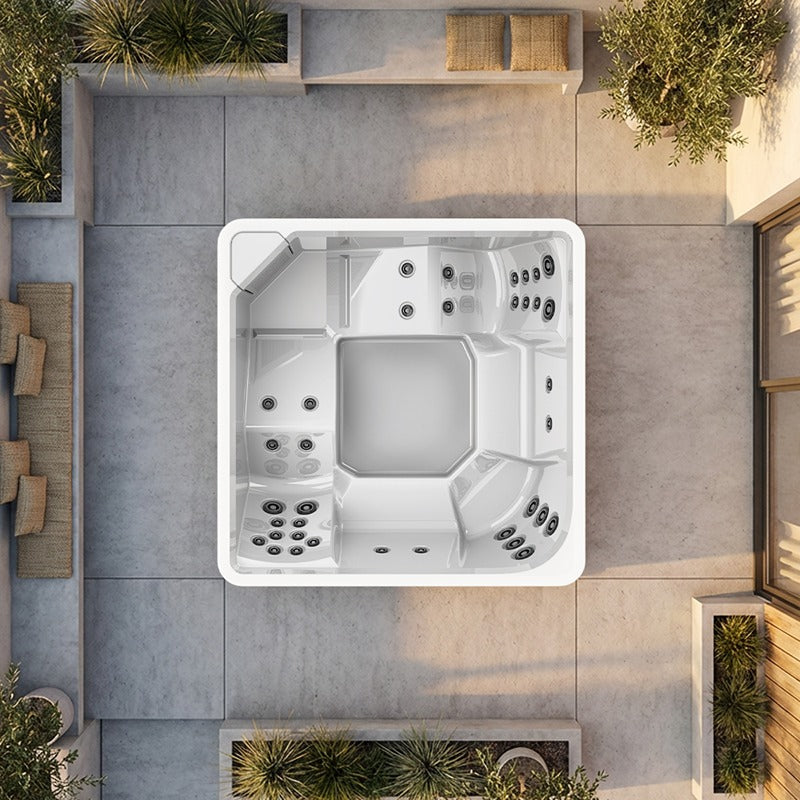 Novitek L-2 Outdoor Whirlpool weiß von oben, quadratisches Design mit Massagedüsen, auf Terrassenfläche mit Pflanzenbegrünung, Vogelperspektive