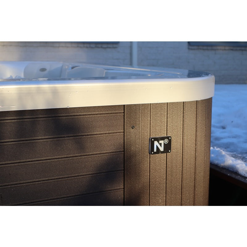 Novitek S-1 Whirlpool mit weißer Wanne, dunkler Holzverkleidung und Herstellerlogo im Außenbereich mit schneebedecktem Umfeld