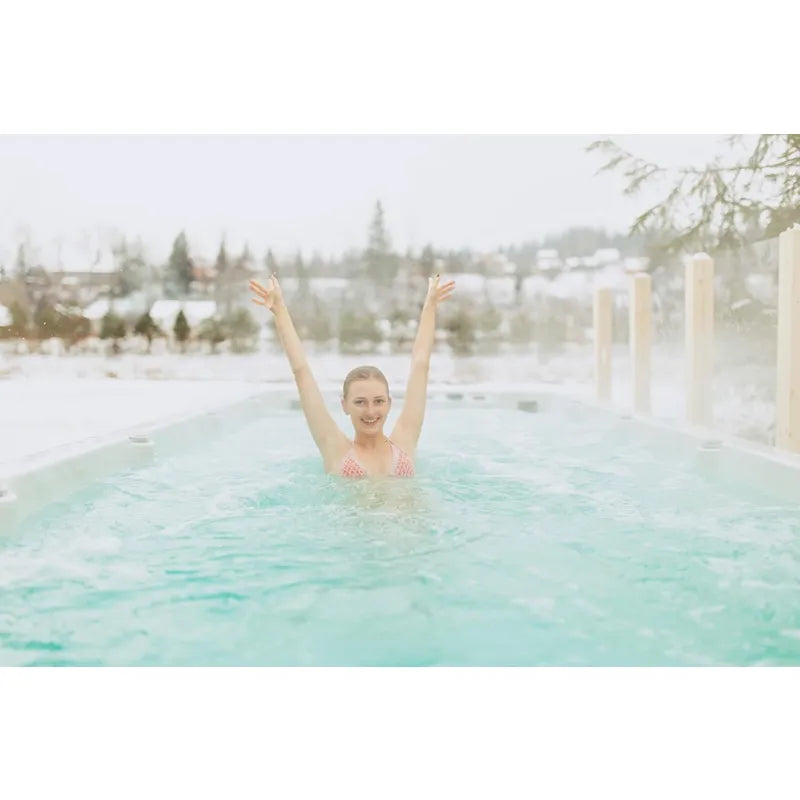 Passion Spas Activity 2 Swim Spa für 3 Personen mit Frau im warmen Wasser, Schneelandschaft im Hintergrund