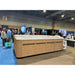 Passion Spas Activity 2 Swim Spa mit moderner Holzverkleidung auf einer Messe, umgeben von Besuchern.