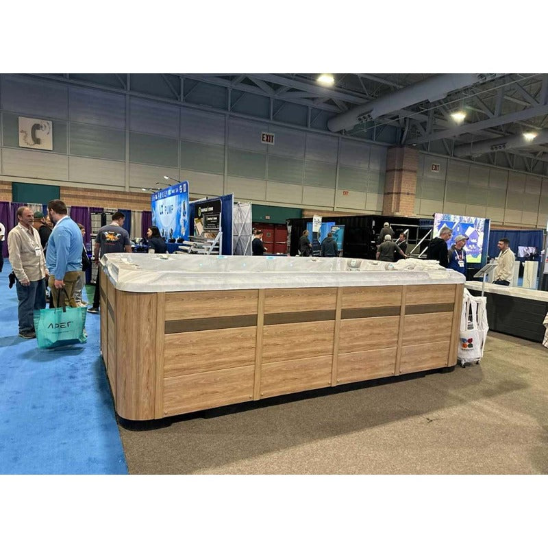 Passion Spas Activity 2 Swim Spa mit moderner Holzverkleidung auf einer Messe, umgeben von Besuchern.