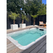 Passion Spas Aquatic 1 Eco Swim Spa für 3 Personen in modernem Garten mit Holzdeck, türkisblauem Wasser und schwarzem Sichtschutz