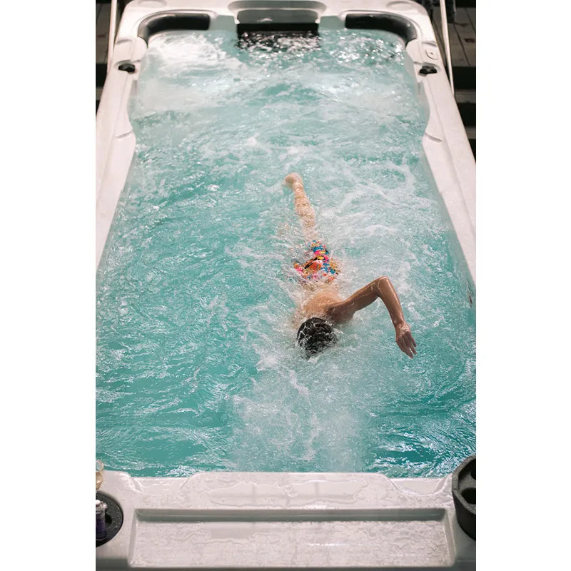 Passion Spas Aquatic 2 Swim Spa: Person schwimmt in weißem Swim Spa mit türkisblauem Wasser