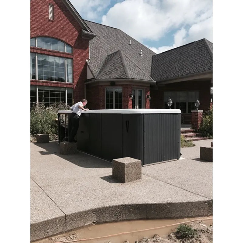 Passion Spas Aquatic 3 Deep Swim Spa für 8 Personen in schwarzem Design vor modernem Backsteinhaus