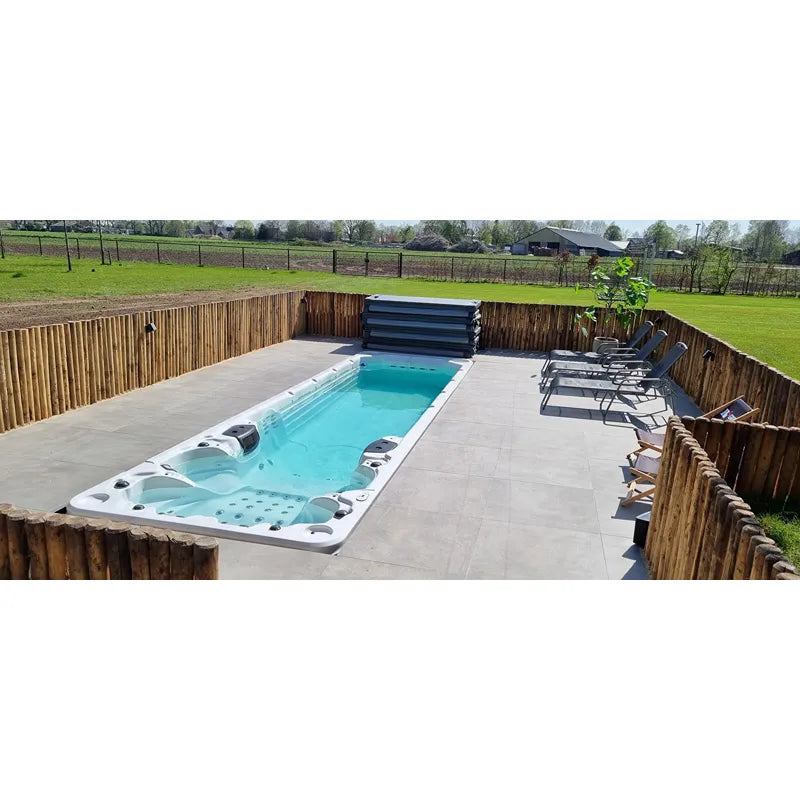 Passion Spas Aquatic 6 Swim Spa für 4 Personen in türkis, eingebaut in Garten mit Holzzaun und Liegen