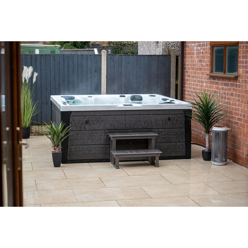 Platinum Spas Onyx Whirlpool in Sterling Silver auf Terrasse mit grauem Sichtschutz – hochwertiger Outdoor-Spa