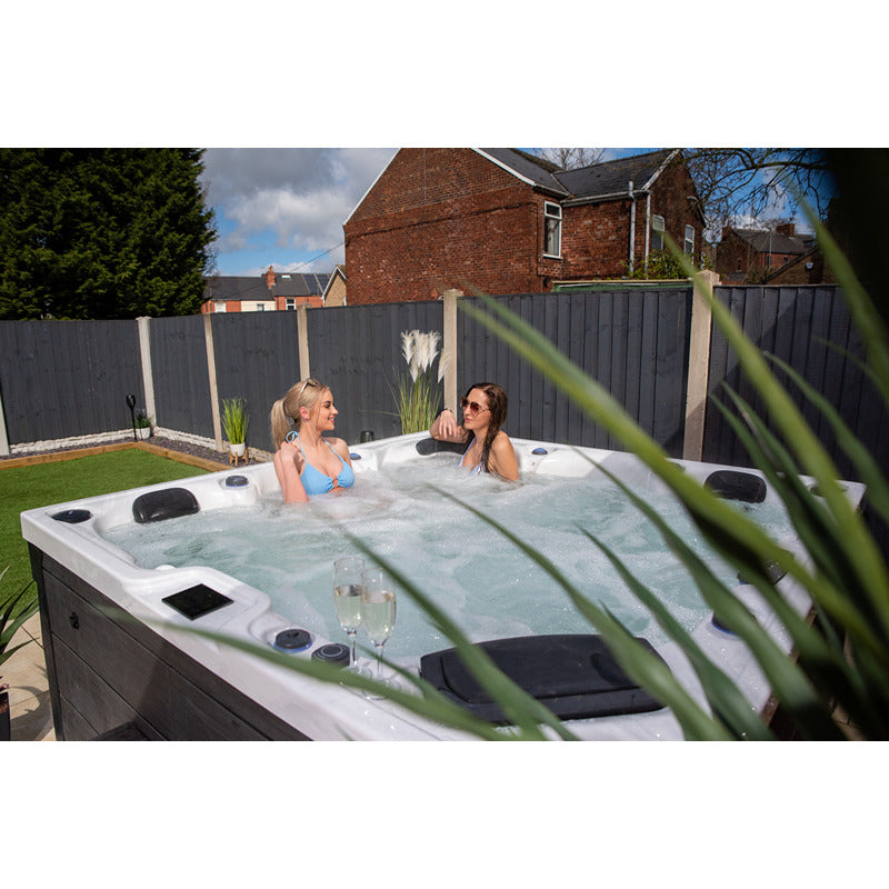 Zwei Frauen genießen den Platinum Spas Onyx Sterling Silver Whirlpool im Garten – entspannte Outdoor-Wellness