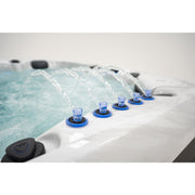 Platinum Spas Barcelona Whirlpool mit mehreren blauen Wasserdüsen, die Wasser in das türkisfarbene Becken spritzen, Detail der Massagefunktion