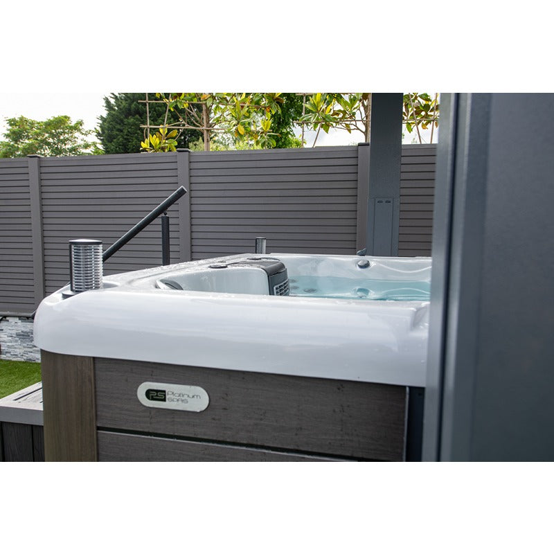 Detailaufnahme des Platinum Spas Eros Swim Spa – weiße Acrylwanne mit grauer Holzverkleidung und Markenemblem im modernen Gartenumfeld
