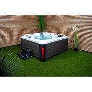 Platinum Spas Kenya Hot Tub stilvoll im Garten platziert, mit Holzverkleidung, Stufenmodul und dekorativer Bepflanzung – elegante Wellness-Oase im privaten Außenbereich.