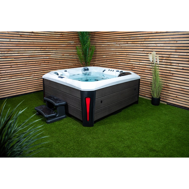 Platinum Spas Kenya Hot Tub stilvoll im Garten platziert, mit Holzverkleidung, Stufenmodul und dekorativer Bepflanzung – elegante Wellness-Oase im privaten Außenbereich.