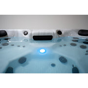 Beleuchteter Innenraum des Platinum Spas Oslo Hot Tubs mit gefülltem Wasserstand – zentrales LED-Licht und Massagedüsen schaffen stimmungsvolle Atmosphäre bei Nacht.