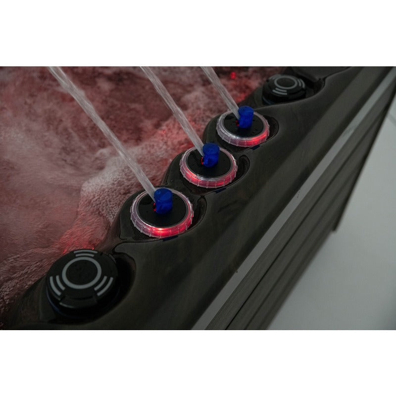 Platinum Spas Seville Whirlpool – Wasserfontänen mit roter LED-Unterbeleuchtung und blauen Reglern auf dunkler Wannenoberkante