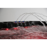 Platinum Spas Seville Whirlpool – Wasserfontänen bei Dunkelheit mit roter LED-Beleuchtung und aufschäumender Wasseroberfläche