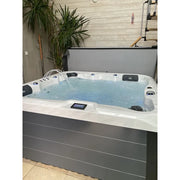 Portcril Double 520 Spa 5-Personen Premium Whirlpool mit türkisblauem Wasser, weißem Rand, schwarzen Kopfstützen und digitaler Steuerung in Showroom