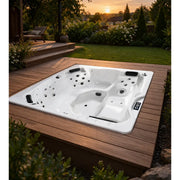 Portcril Emotion 5 Whirlpool für 5 Personen in eine Holzterrasse eingelassen, Draufsicht auf die Düsenanordnung mit 31 Jets, bei Sonnenuntergang im Garten.