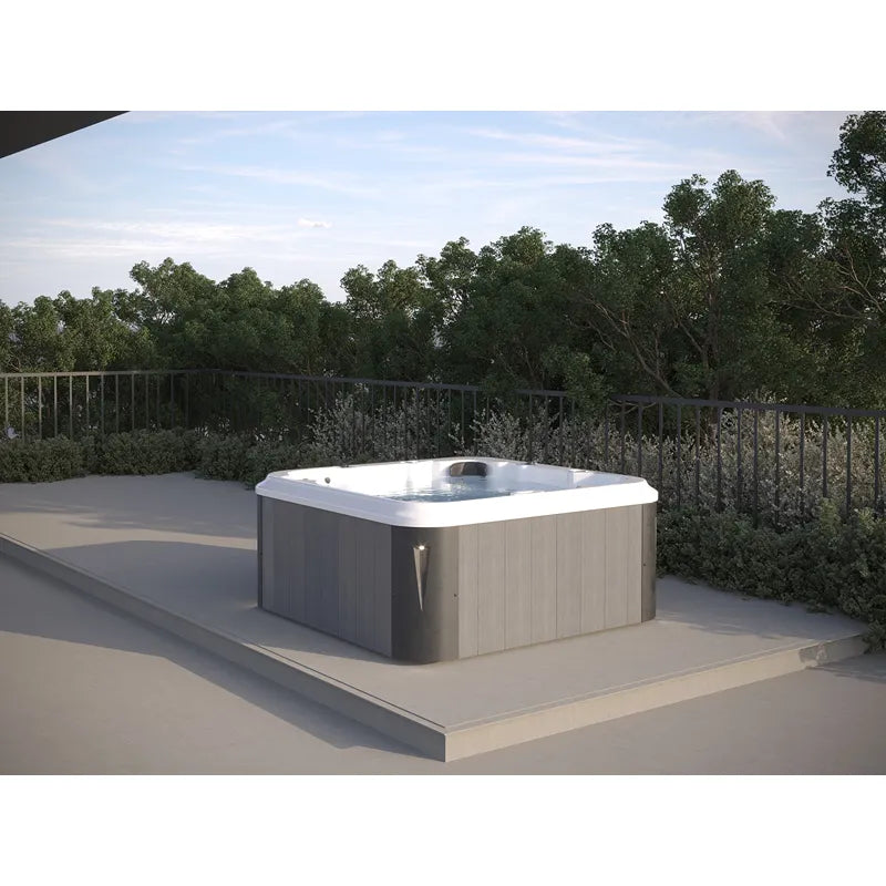 Portcril Essential 4 Spa 4-Personen Whirlpool mit weißem Rand auf sonniger Terrasse mit Gartenbäumen