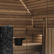 Termo Pure Innensauna von Savne Štrus - Innenraum mit wärmebehandeltem Holz, Holzbänken und schwarzem Ofen