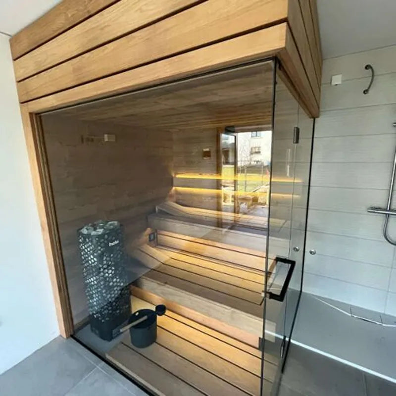 Tyrol Innensauna - Alpenländisches Design von Savne Štrus mit Glasfront, Holzbänken und Saunaofen im Badezimmer